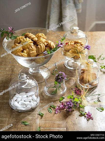 Biscuits and sugared almonds in glass jars bowls