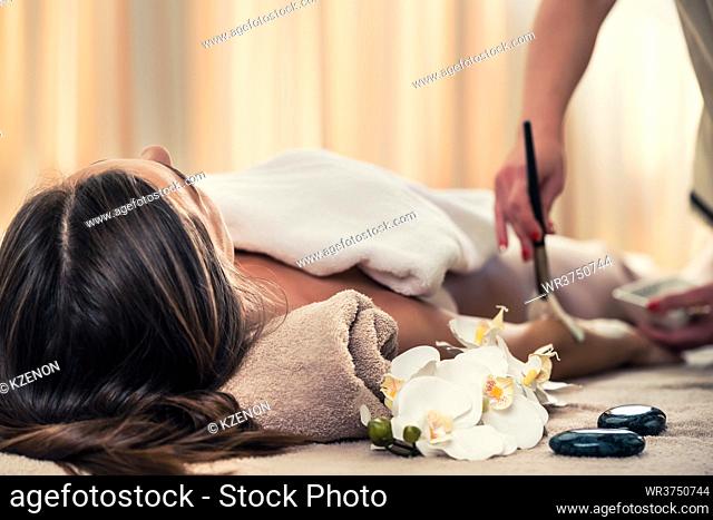 Woman lying down on massage bed during Asian anti-aging treatment with organic moisturizer at beauty center