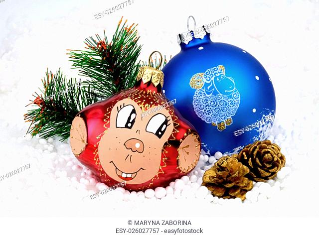 Christmas tree toys monkey, a balloon with the sheep, artificial fir branch, two cones on the background of artificial snow