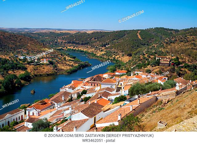 View of Guadiana river bend and residential houses of Mertola city on the riverside as seen from the Castle hill. Mertola. Baixo Alentejo. Portugal