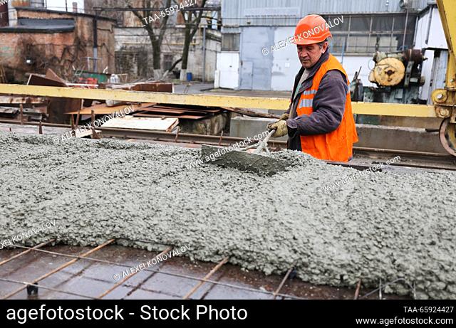 RUSSIA, ZAPOROZHYE REGION - DECEMBER 19, 2023: An employee levels fresh concrete at a plant of reinforced concrete structures in the city of Berdyansk
