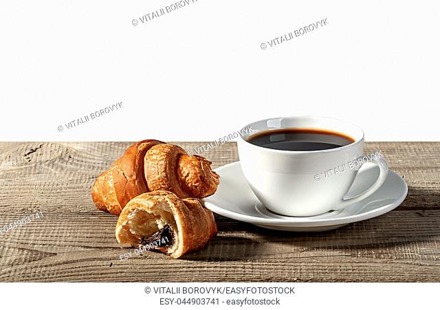 Coffee and croissants on a wooden table. Broken croissant. Isolated on white background