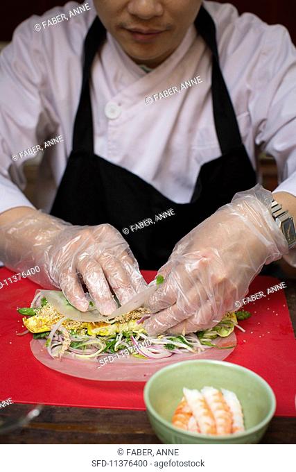 A chef preparing a Vietnamese spring roll with tofu