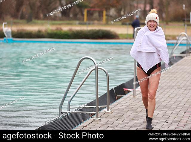 10 December 2023, Saxony-Anhalt, Osterwieck: A participant in the Advent swim enters the water at 6 degrees Celsius in the Osterwieck outdoor pool