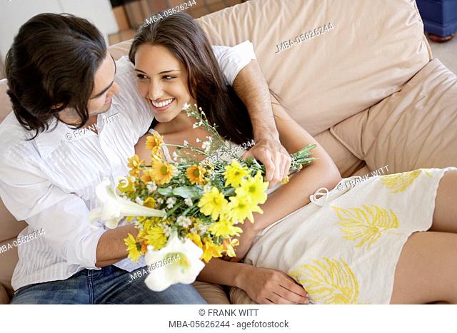 Young couple with flowers on couch