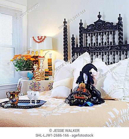 Halloween: Bed decorated for halloween with folk art witch. Hand carved headboard, vintage linens, french milk glass goblets and tray sit on be, orange mums
