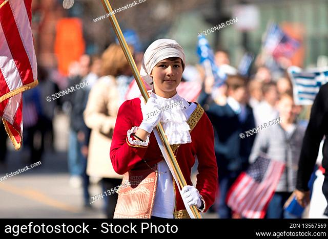 Chicago, Illinois, USA - April 29, 2018 Greek girl wearing traditional clothing carrying the american flag at the Greek Independence Day Parade