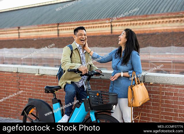 Happy mature couple with electric bicycle by wall