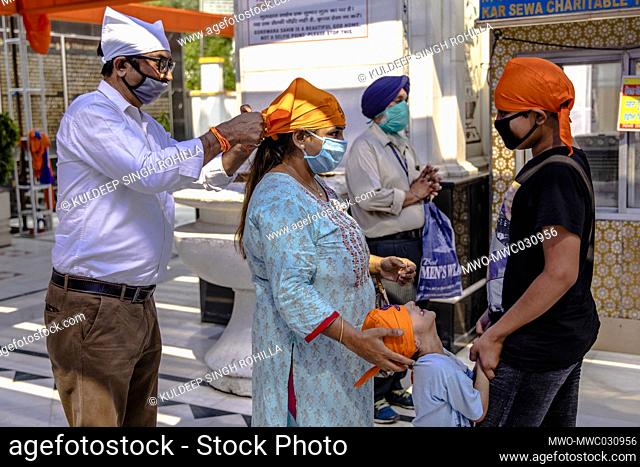 A indian family wearing headgear before entering Bangla Sahib Gurudwara after the opening of most of the religious places as India eases lockdown restrictions...