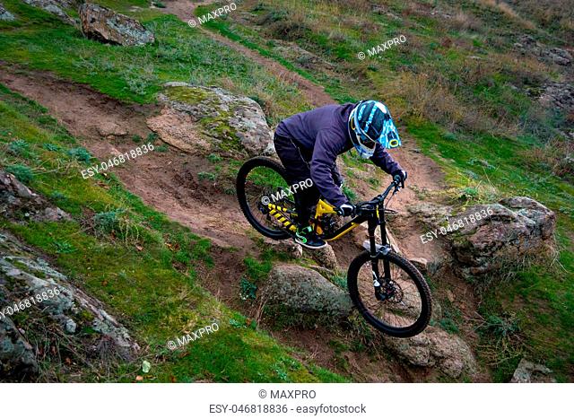 Professional Cyclist Riding Mountain Bike Down the Rocky Hill. Extreme Sport and Enduro Biking Concept