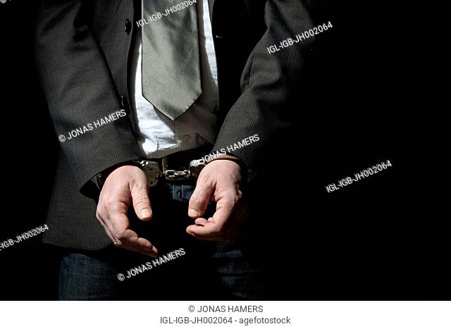 Picture shows a Handcuffed businessman on a black background
