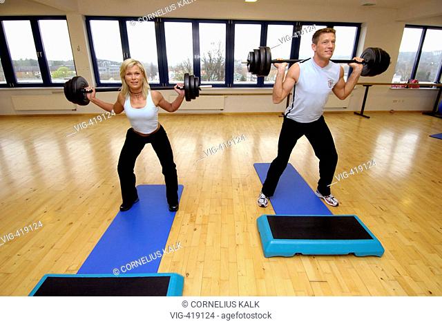 Man and woman is exercising with a dumbbell within a gym  - Geesthacht, Schleswig-Holstein, GERMANY, 06/04/2007