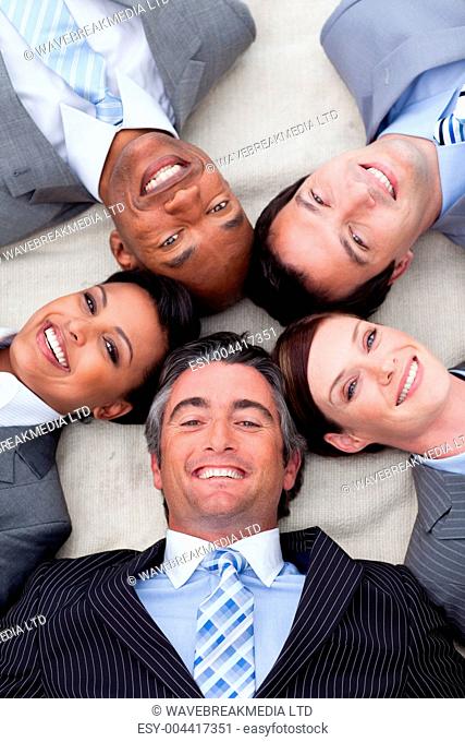 Smiling business team lying on the floor with heads together