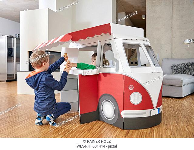 Brother and sister with popsicles and model ice cream van in living room