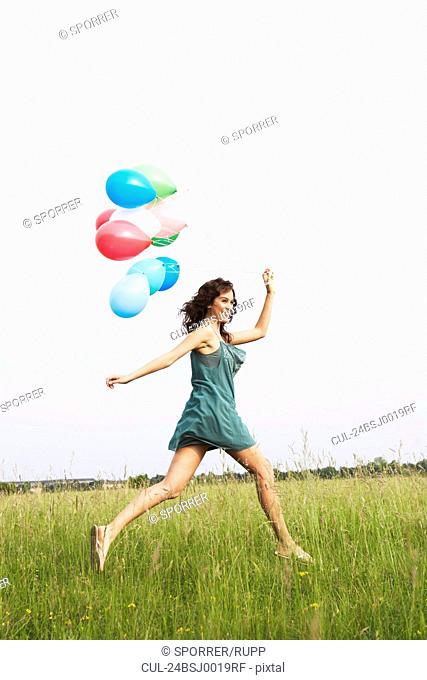 Woman with air balloons jumping