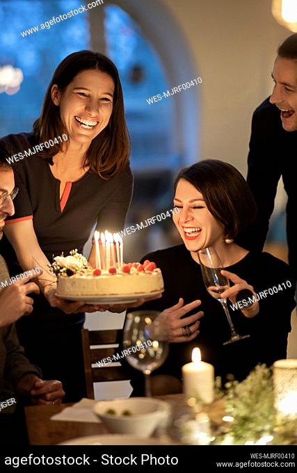 Male and female friends laughing during birthday celebration at home