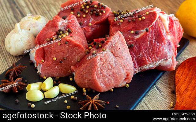 Red meat on a black Board sprinkled with pepper, garlic, anise and lime. Billets for barbecue, steak or shish kebabs. Cooking for lunch the fresh diet of red...