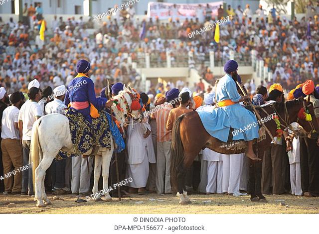 People watching stunts of Nihangs or Sikh warrior ; during cultural events for 300th year's celebrations of Consecration of perpetual Sikh Guru Granth Sahib at...