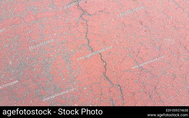Red colored damaged road or paved pathway with crackes of different shpaes. Cracked texture with copy space for text and messages
