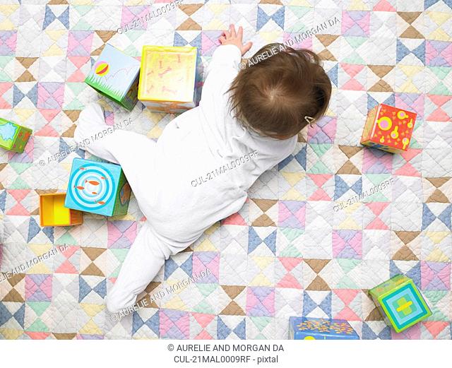 Baby with cubes on quilt