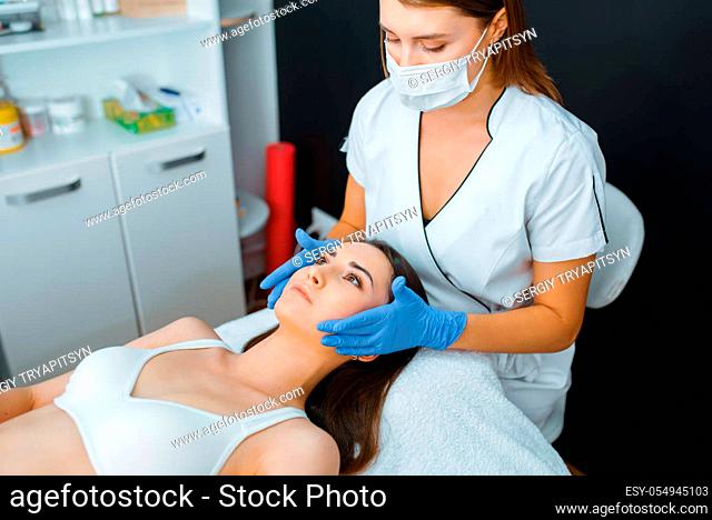 Cosmetician in gloves and female patient on treatment table. Rejuvenation procedure in beautician salon. Doctor and woman, cosmetic surgery against wrinkles