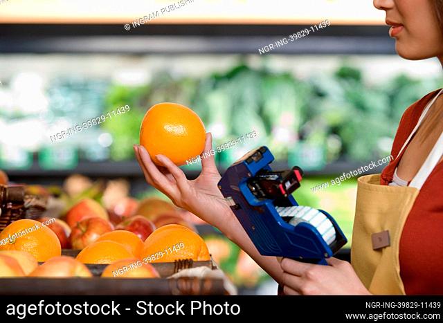 sales assistant pricing an orange