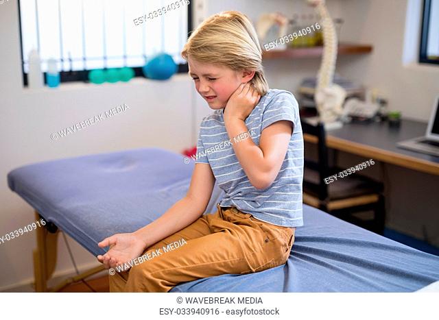 Boy sitting on bed with neck ache
