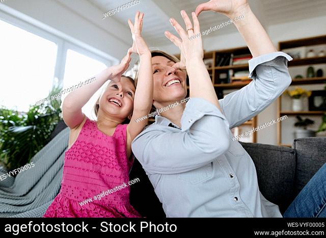 Portrait of happy mother and her little daughter sitting together on the couch having fun