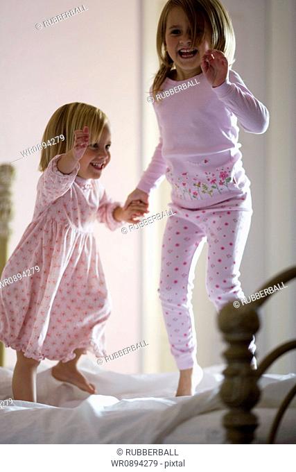 Two girls jumping on the bed