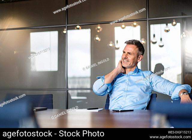 Smiling male entrepreneur looking away while sitting at work place