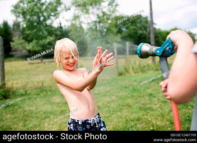 Canada, Ontario, Kingston, Boys (8-9, 14-15) playing with water from hose
