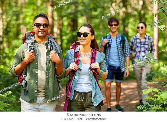 group of friends with backpacks hiking in forest