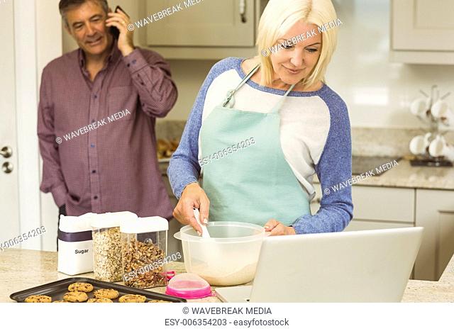 Happy blonde preparing dough with husband behind