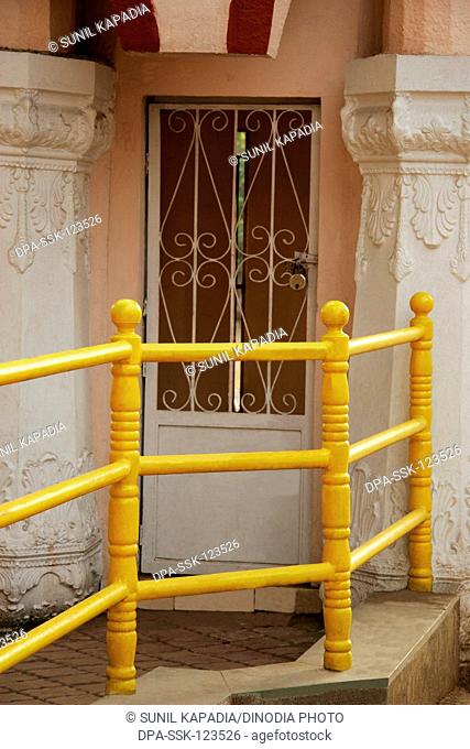 Yellow iron railing going towards two carved pillars and locked door ; Pune ; Maharashtra ; India