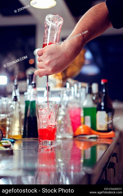 Bartender coocks cocktail behind a bar counter