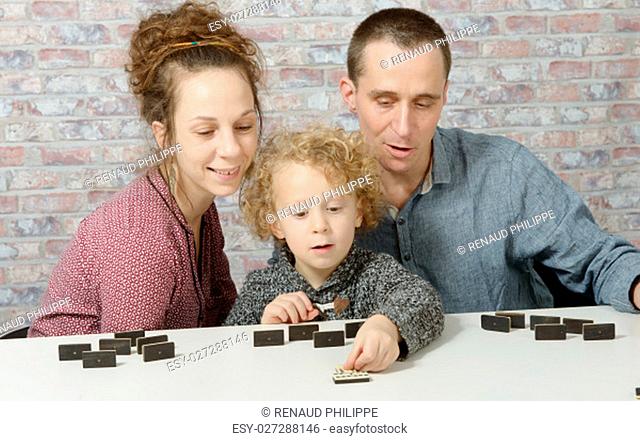 happy family mother, father and child playing dominos