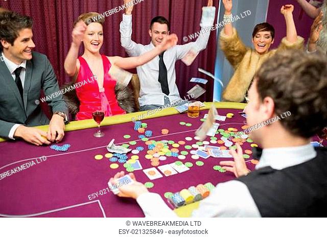 People sitting celebrating at poker game in casino
