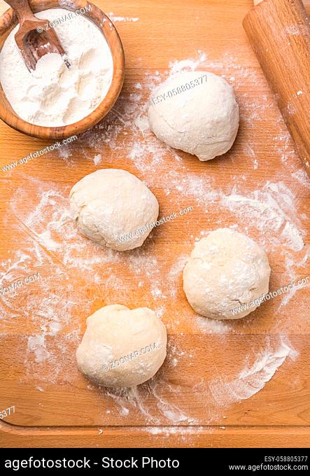 Freshly prepared yeast dough for pizza or bread on wooden background. Home cooking concept