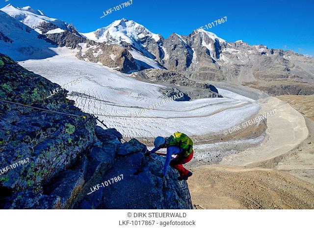 Woman climbing the via ferrata at Piz Trovat with view to Bellavista (3922 m), Piz Bernina (4049 m), Piz Morteratsch (3751 m) as well as Pers- and Morteratsch...