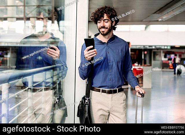 Happy businessman using smart phone at railroad station
