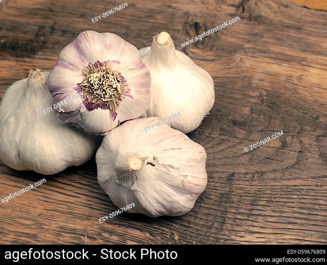 Four bulbs of garlic on a rustic kitchen table, view from above, healthy eating concept