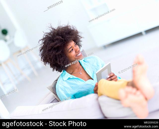 Young african american woman at home relaxing in her luxury lliving room reading a digital tablet surf internet and work