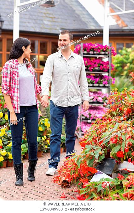 Couple walking in garden centre while smiling and holding hands