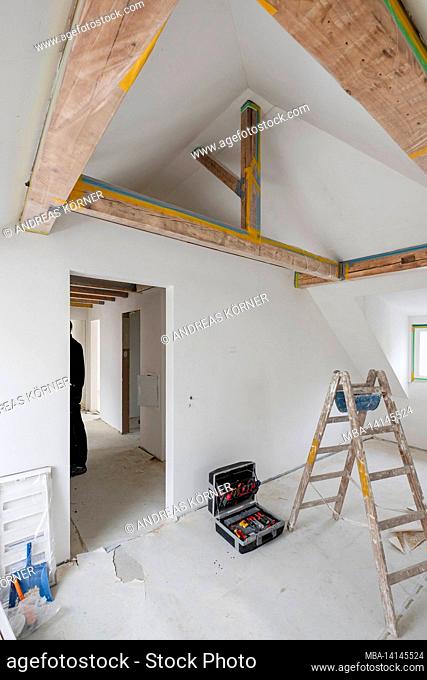 construction site, refurbishment and renovation of an apartment, empty room in the attic with a wooden beam ceiling