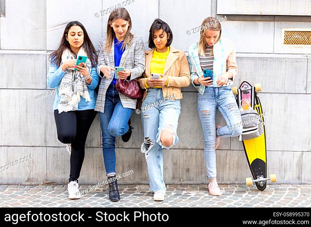 Group of beautiful young female friends of different race using smart mobile phones app, Teenagers addiction to new technology trends, showing Concept of youth