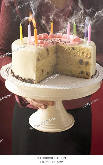 Woman serving birthday cake with blown-out candles