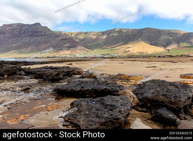 Coastline and sand beach Playa de Famara with mountain range and ocean waves in the north west of canary island Lanzarote, Spain