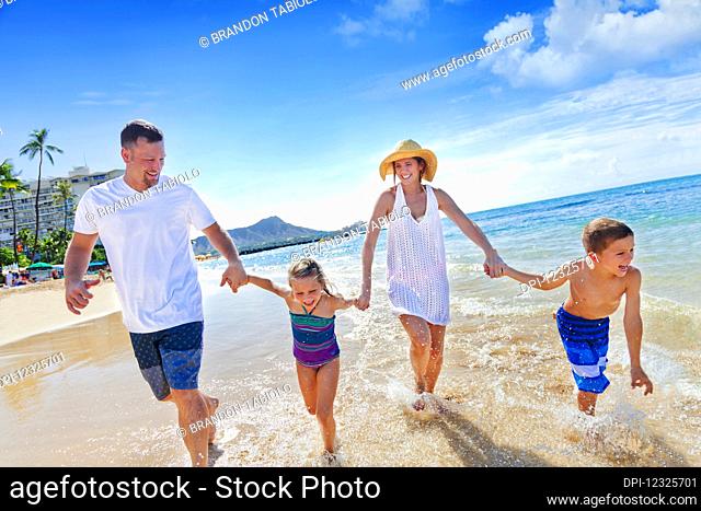 Family of four enjoying a summer vacation in Waikiki Beach; Honolulu, Oahu, Hawaii, United States of America