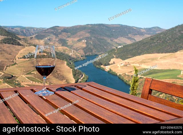 Glass of red wine or port for tasting above the hillsides of the Douro valley in Portugal