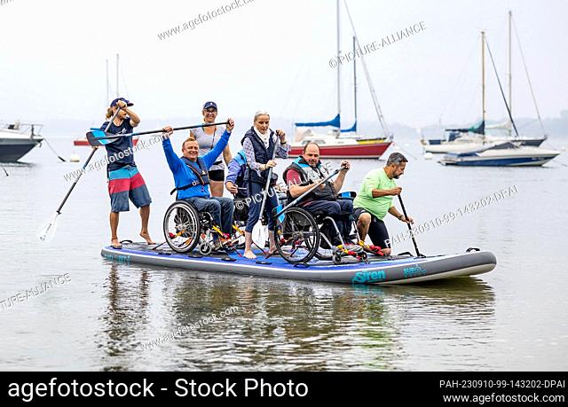 10 September 2023, Schleswig-Holstein, Eckernförde: Participants of the wheelchair SUP event ""Rolli on SUP"" on the Baltic Sea paddle along the shore of Borby